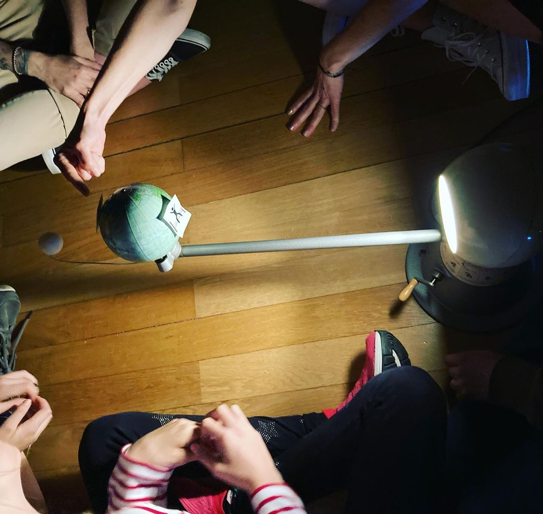 Kinderhände, die auf ein Modell des Erde-Sonne-Mond-Systems zeigen